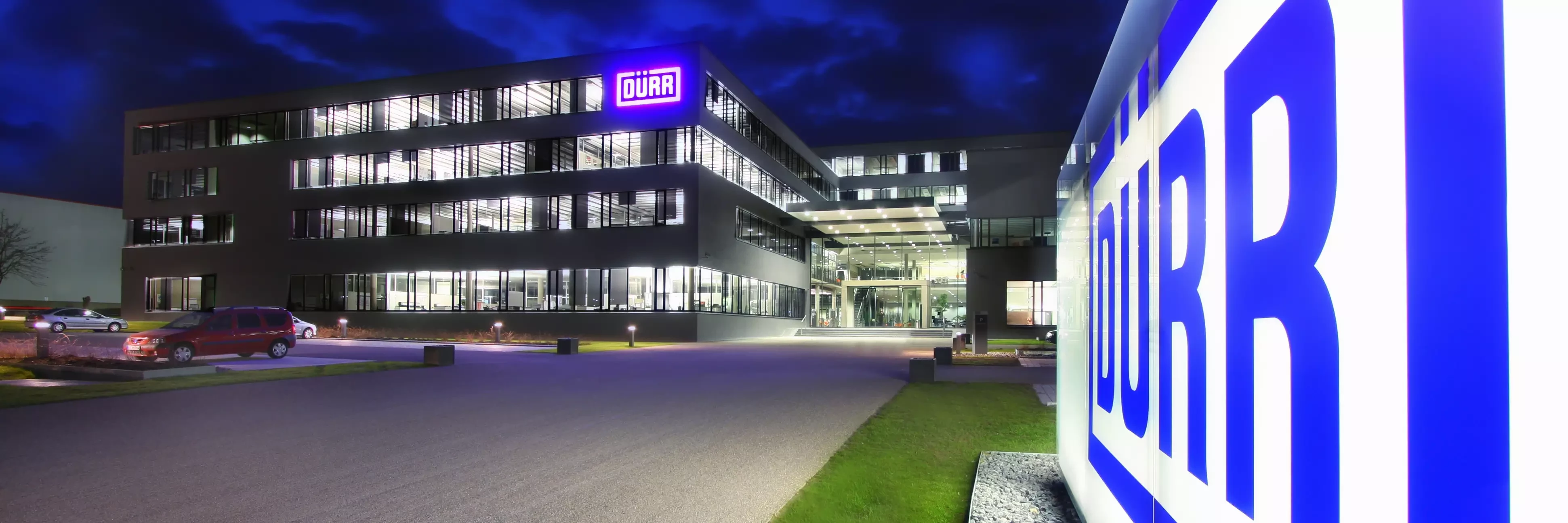 Dürr location headquarters in germany at night viewing the shining logo in the front of the building.